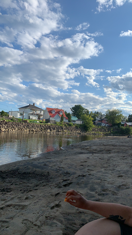 Personne assise sur une plage privée de Baie-St-Paul. On y voit des maisons.